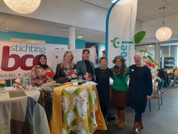 Zes vrouwen op een horizontale lijn tegen kleurrijke achtergrond