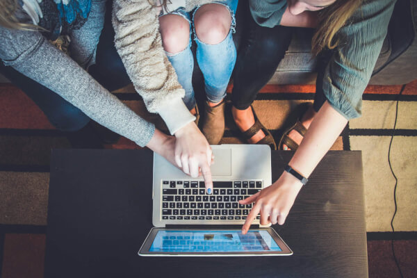 Jongeren rond een laptop op schoot