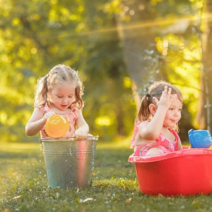 cute little blond girls playing with water splashes field summer verkleind